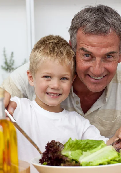 Szczęśliwy dziadek gotowanie sałatka z wnukiem — Zdjęcie stockowe