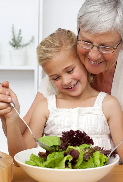 Glückliche Großmutter kocht mit Enkelin einen Salat — Stockfoto