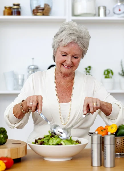 Happy senior woman cooking a salad — Stock Photo, Image