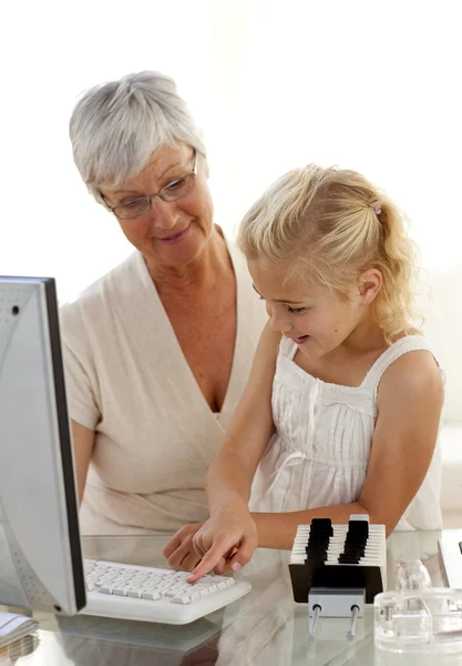 Enkelin erklärt Großmutter die Bedienung eines Computers — Stockfoto