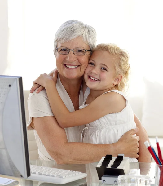 Vnučka a babička objímání a pomocí počítače — Stock fotografie