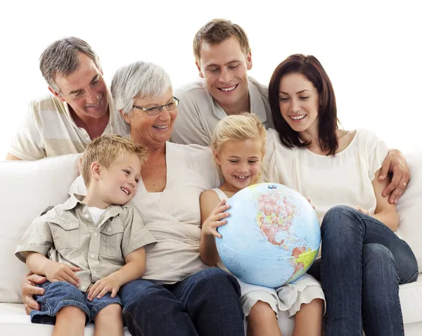 Grande famiglia sul divano guardando un globo terrestre — Foto Stock