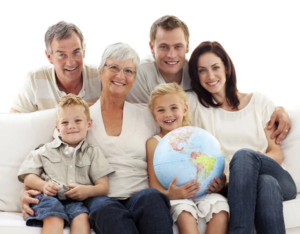 Grande família no sofá segurando um globo terrestre — Fotografia de Stock