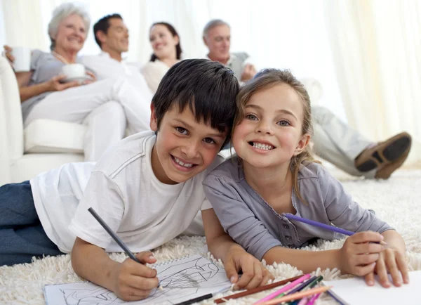 Children painting on floor with their family in sofa — Stock Photo, Image