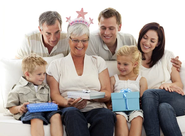 Family giving a gift to grandmother for her birthday — Stock Photo, Image