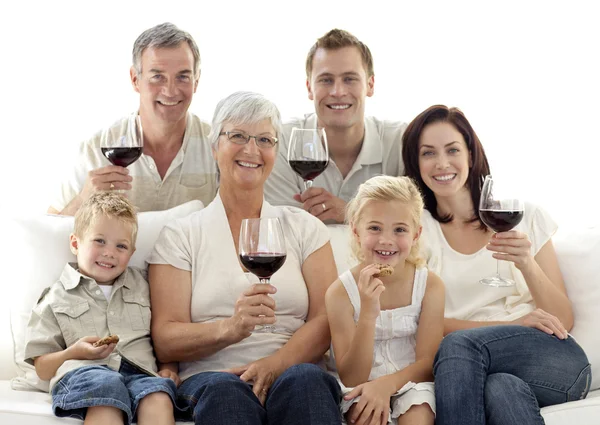 Family in living-room drinking wine and eating biscuits — Stock Photo, Image
