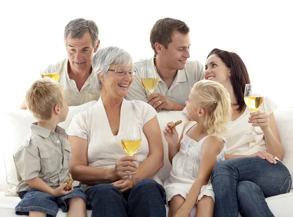 Familjen i vardagsrummet dricka vin och äta kex — Stockfoto