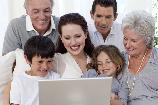 Famiglia seduta sul divano con un computer portatile — Foto Stock