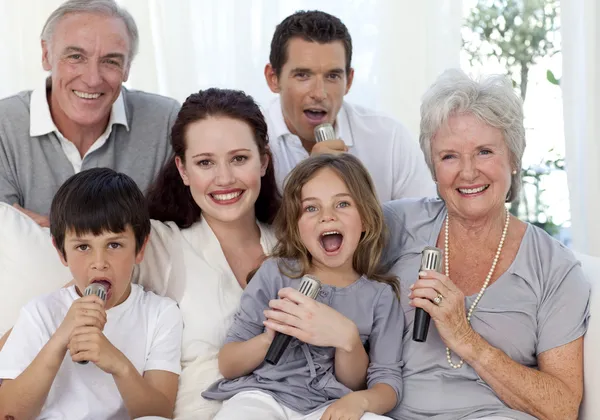 Счастливая семья поет караоке в гостиной — стоковое фото