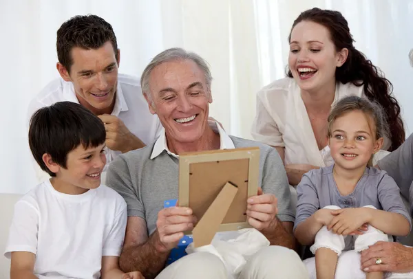 Дедушка смотрит на фото со своей семьей — стоковое фото