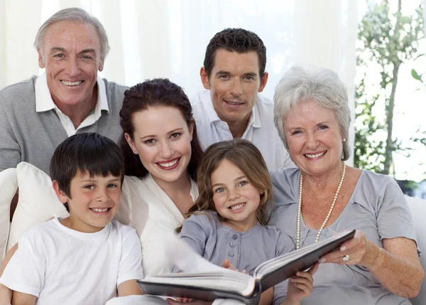 Família sorrindo olhando para um álbum de fotos — Fotografia de Stock