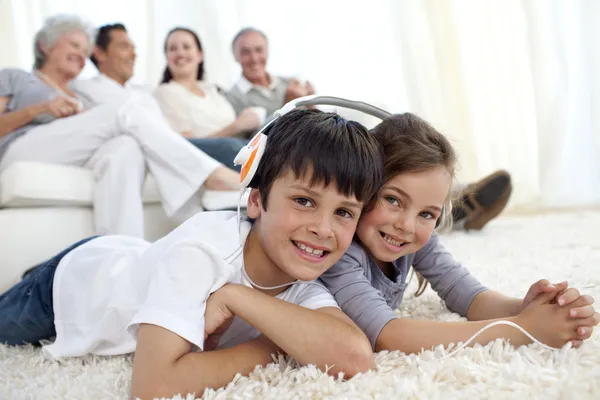 Children on floor listening to the music in living-room — 图库照片