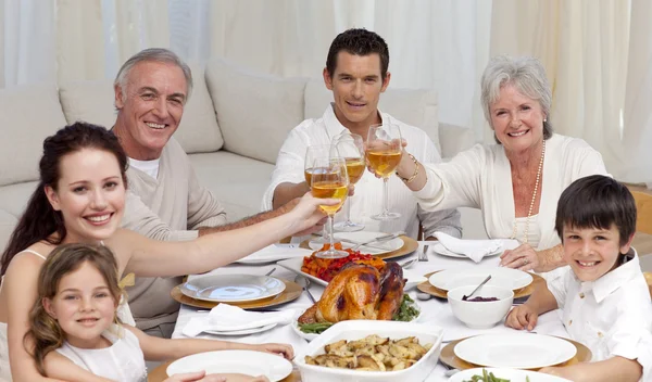 Glad familj tusting med vin i en middag — Stockfoto