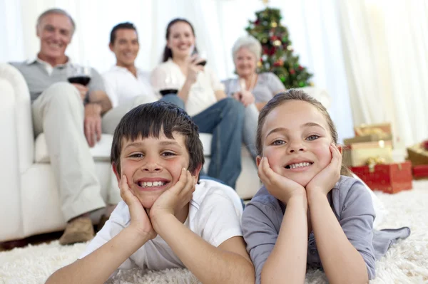 Брат и сестра на полу со своей семьей в Рождество — стоковое фото