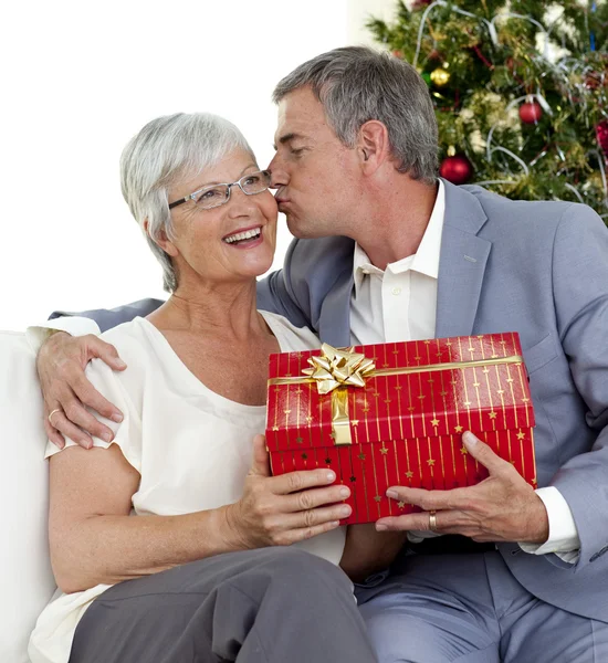 Starszy mężczyzna daje całusa i prezent świąteczny żonie — Zdjęcie stockowe