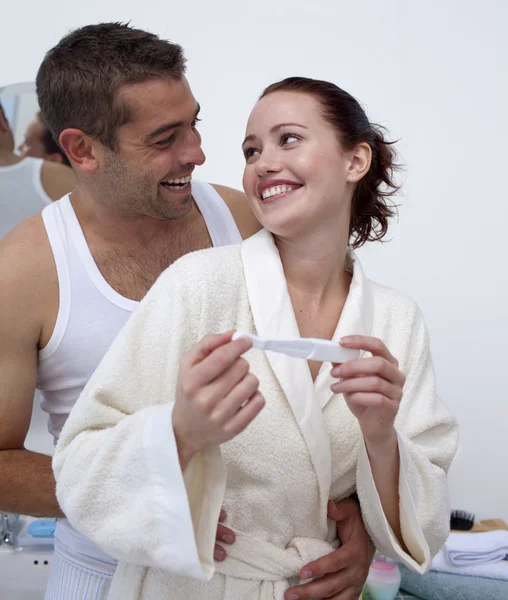 Casal feliz no banheiro segurando um teste de gravidez — Fotografia de Stock