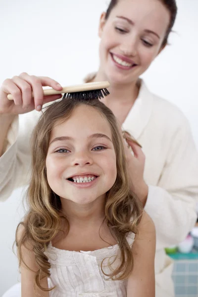 Portrait of mother doing her daughter's hair — Stock Photo, Image
