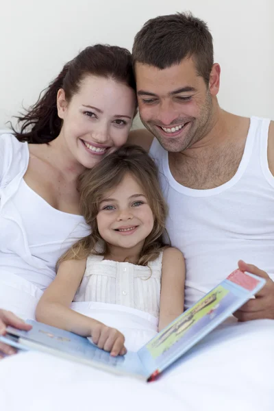 Parents and daughter reading in bed — Stock Photo, Image
