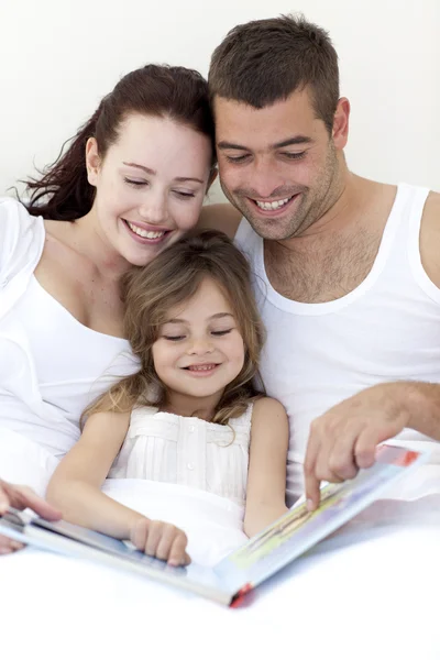 Mladá rodina čtení v posteli — Stock fotografie