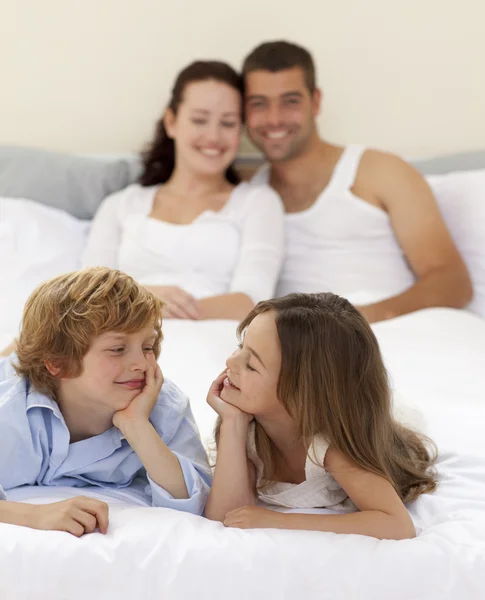 Bruder und Schwester schauen sich im Bett mit ihren Eltern an — Stockfoto