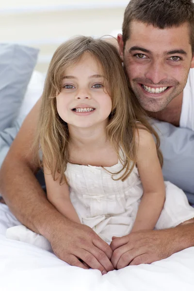 Portrait of smiling father and daughter in bed — Stock Photo, Image