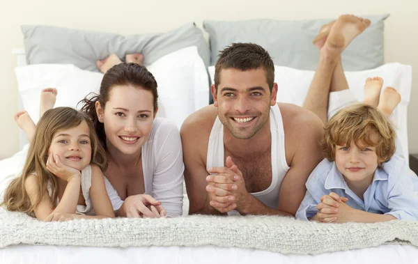 Портрет счастливой семьи лежащей в постели — стоковое фото