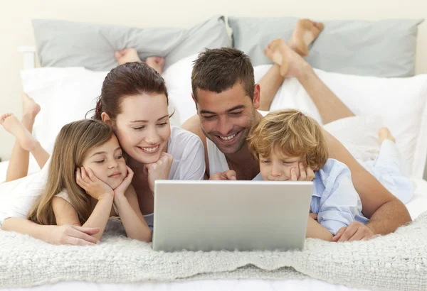 Famiglia a letto con un computer portatile — Foto Stock
