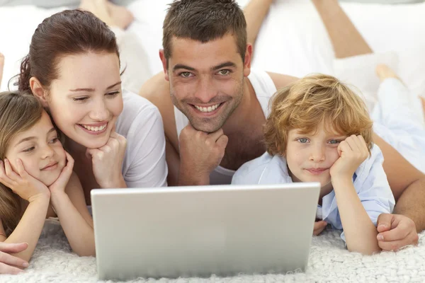 Pais e crianças na cama usando um laptop — Fotografia de Stock
