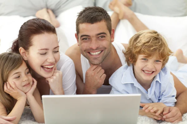 Familie in bed met plezier met een laptop — Stockfoto