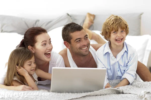 Famille heureuse au lit en utilisant un ordinateur portable — Photo