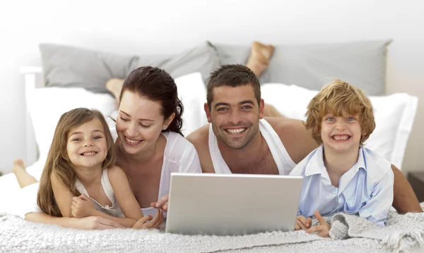Familia en la cama usando un portátil — Foto de Stock