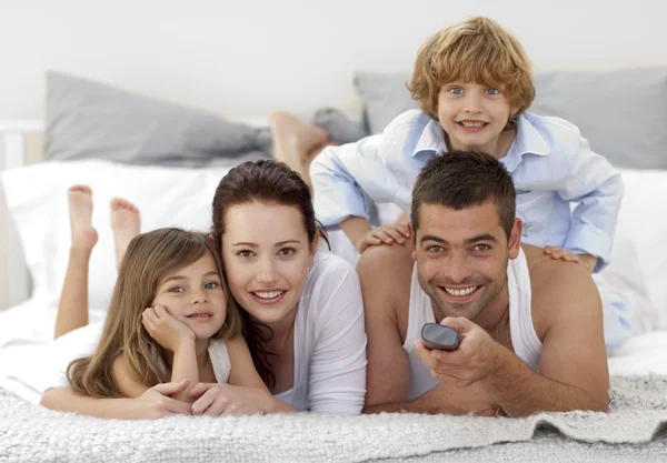 Family lying in bed and using a remote — Stock Photo, Image