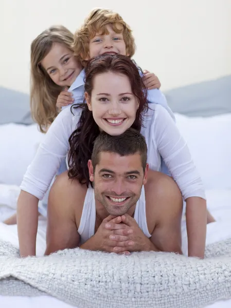 Портрет счастливых родителей и детей, веселящихся в постели — стоковое фото