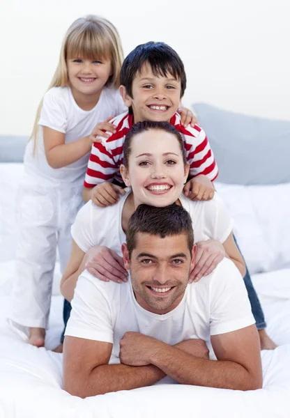 Happy family playing in bed together — Stock Photo, Image