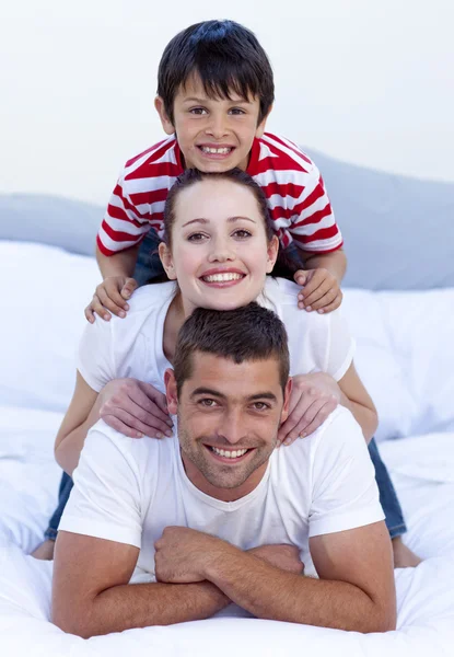 Happy parents and son playing in bed — Stock Photo, Image