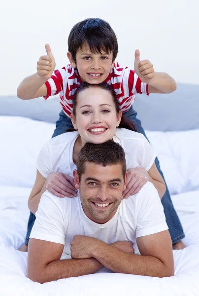 Šťastní rodiče a syna v posteli s palec nahoru — Stock fotografie