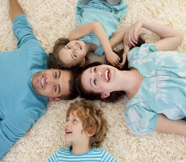 Sonriente familia en el suelo con cabezas juntas —  Fotos de Stock