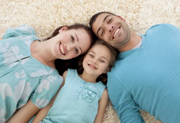Sorrindo pais e menina no chão com as cabeças juntas — Fotografia de Stock