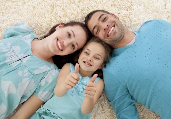 Pais e menina no chão com os polegares para cima — Fotografia de Stock