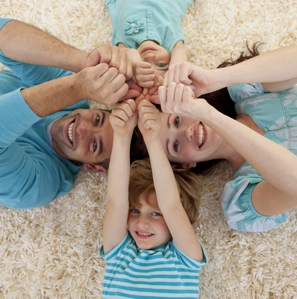 Alto ângulo de família no chão com as cabeças e as mãos juntas — Fotografia de Stock