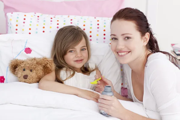 Krankes kleines Mädchen im Bett nimmt Hustenmittel — Stockfoto