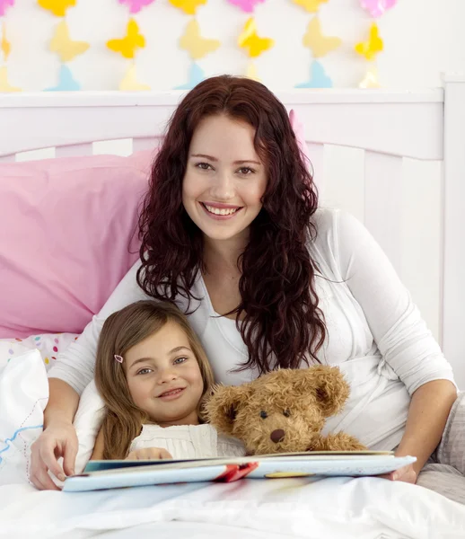 Uśmiechający się matka i córka czytania w łóżku — Zdjęcie stockowe