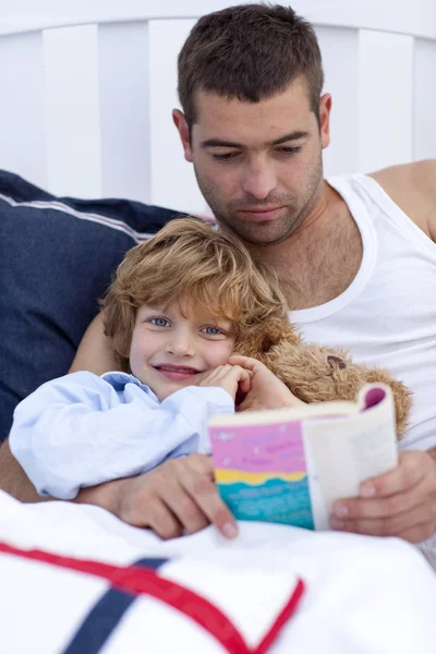 Ο μικρός γιος ανάγνωση με τον πατέρα του στο κρεβάτι — Φωτογραφία Αρχείου