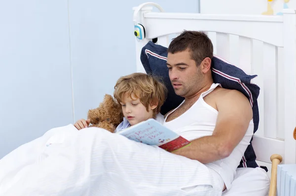 Father and son reading a book in bed — Stock Photo, Image
