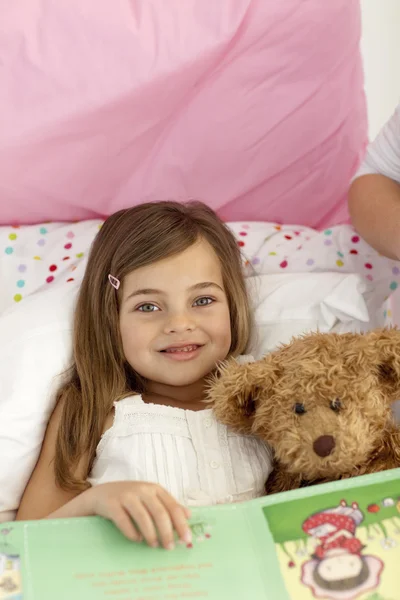 Klein meisje het lezen van een boek in bed — Stockfoto