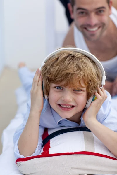 Son listening to music in bed with his father — Stock Photo, Image