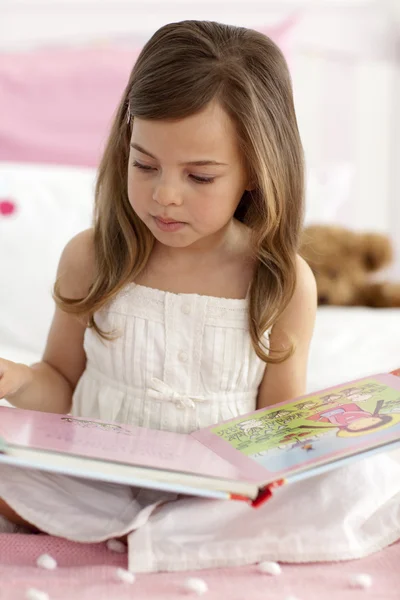 Malá holčička čtení v posteli — Stock fotografie