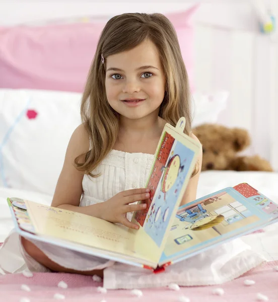 Beautiful little girl reading in bed — Stock Photo, Image
