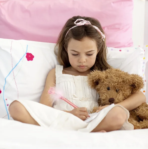 Kis lány az ágyban írás — Stock Fotó