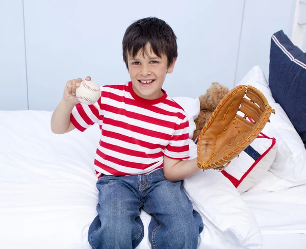 Menino feliz jogando beisebol na cama — Fotografia de Stock